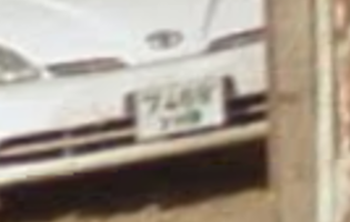 Zoomed in screenshot of a car’s license plate in `7.png`